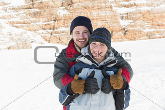 Happy loving couple gesturing thumbs up on snow