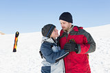 Happy loving couple with ski board on snow in background