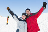 Couple raising hands with ski board on snow in background