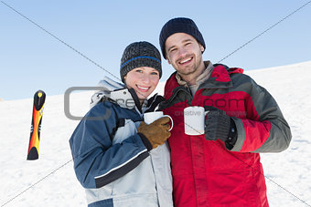 Couple having coffee with ski board in snow