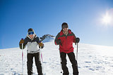 Skiers on snow covered landscape against blue sky