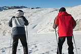 Rear view of a couple with ski poles on snow