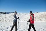 Portrait of a smiling couple with ski poles on snow