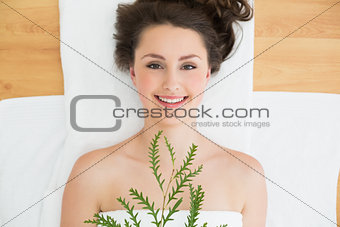Brunette lying with leaves in beauty salon
