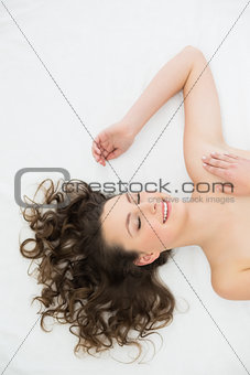 Smiling young brunette sleeping in bed