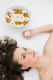 Beautiful woman lying with bowl of flowers in beauty salon