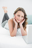 Smiling casual brunette with laptop in bed