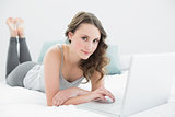Casual young brunette using laptop in bed