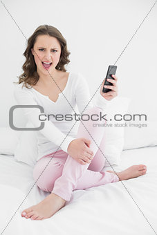 Cheerful woman with mobile phone in bed