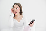Shocked woman with mobile phone looking away