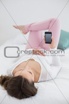 Relaxed woman looking at mobile phone in bed
