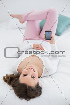 Relaxed young woman with mobile phone in bed