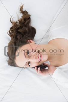 Young brunette using mobile phone in bed