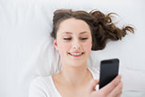Young brunette looking at mobile phone in bed