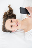 Young brunette with mobile phone in bed