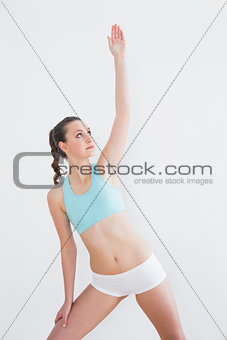 Sporty female stretching hand in fitness studio