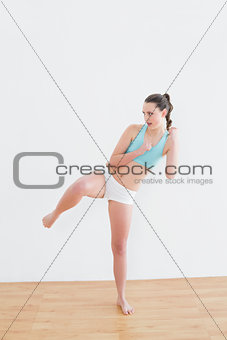 Sporty fit woman performing an air kick in fitness studio