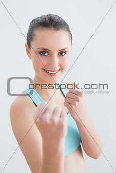 Smiling fit woman clenching fists against wall
