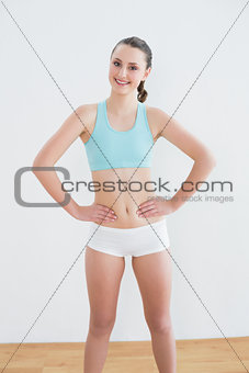 Smiling toned woman standing in fitness studio