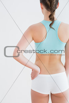 Rear view of toned woman with hand on hip against wall