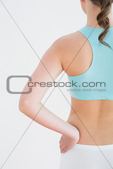 Toned woman with hand on hip against wall