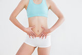 Fit woman with hands on belly against wall