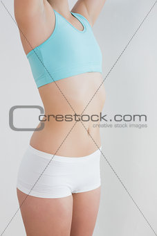 Mid section of toned woman stretching against wall