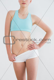 Mid section of toned woman standing against wall
