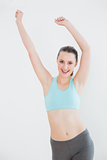 Smiling toned woman stretching hands against wall