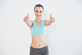 Toned woman gesturing thumbs up against wall