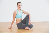 Fit woman sitting in cowface posture in fitness studio
