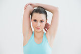 Toned woman stretching hands behind head against wall