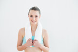 Fit young woman with towel around neck against wall