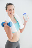 Woman with dumbbells and water bottle against wall