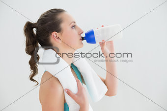 Side view of fit woman drinking water at the gym