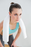 Tired woman with towel around neck at fitness studio