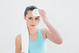 Close up of woman wiping sweat with towel against wall
