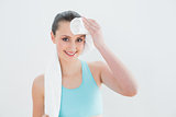 Woman wiping sweat with towel against wall