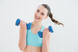 Portrait of woman with dumbbells against wall