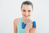 Portrait of woman with dumbbell against wall