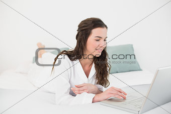 Relaxed casual brunette using laptop in bed