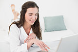 Relaxed smiling brunette using laptop in bed