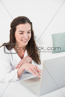 Relaxed smiling casual brunette using laptop in bed
