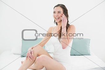 Relaxed young woman using mobile phone in bed