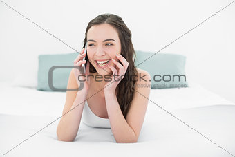 Cheerful relaxed woman using mobile phone in bed