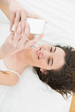Relaxed young woman text messaging in bed
