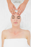 Hands massaging a beautiful woman's forehead at beauty spa