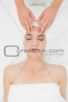 Hands massaging a beautiful woman's forehead at beauty spa
