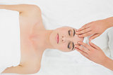 Hands massaging a woman's forehead at beauty spa