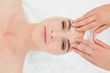 Hands massaging woman's forehead at beauty spa